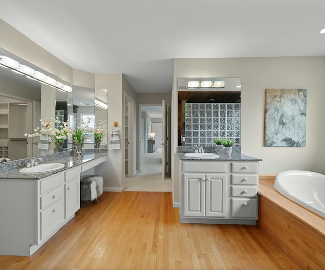 bathroom with vanity, a tub, and wood-type flooring