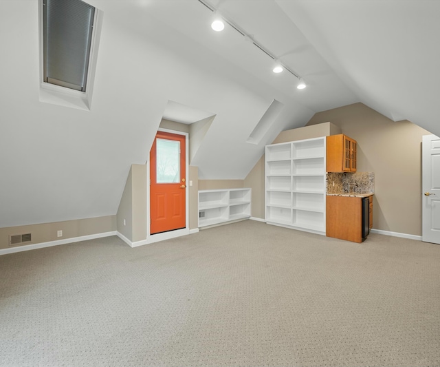 additional living space featuring light colored carpet, vaulted ceiling, and built in features