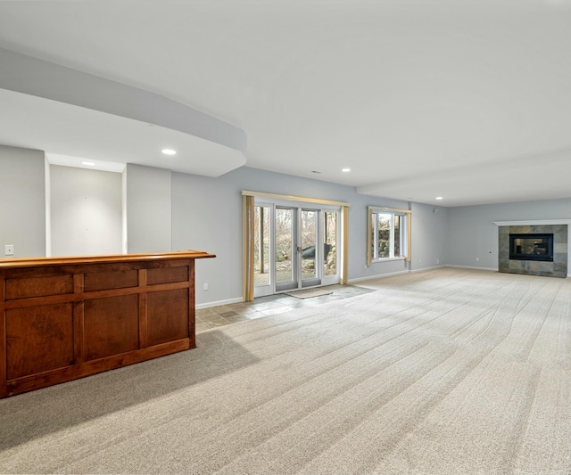 unfurnished living room featuring a tiled fireplace and light carpet