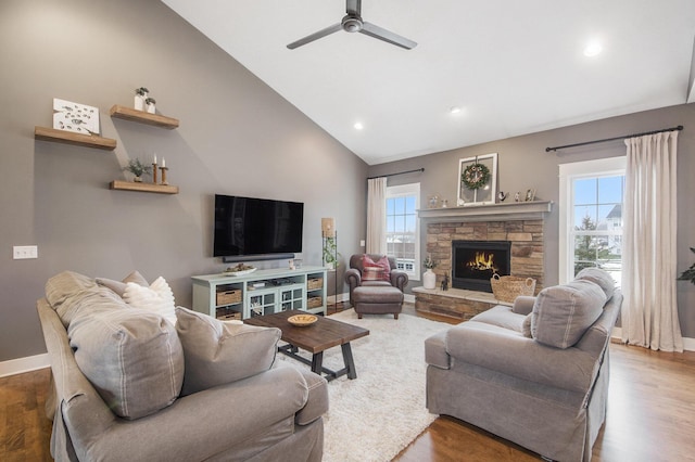 living room featuring wood-type flooring, a stone fireplace, high vaulted ceiling, and ceiling fan