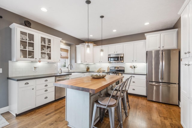 kitchen with white cabinetry, appliances with stainless steel finishes, butcher block countertops, and pendant lighting