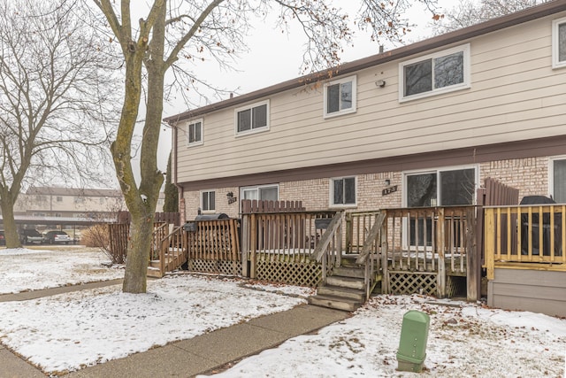 snow covered house featuring a wooden deck