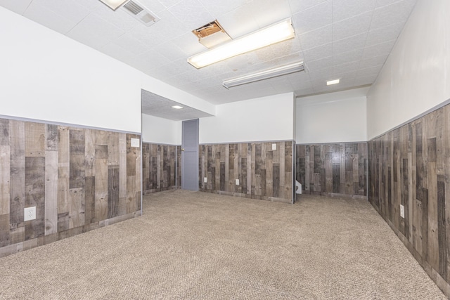 carpeted spare room featuring wooden walls