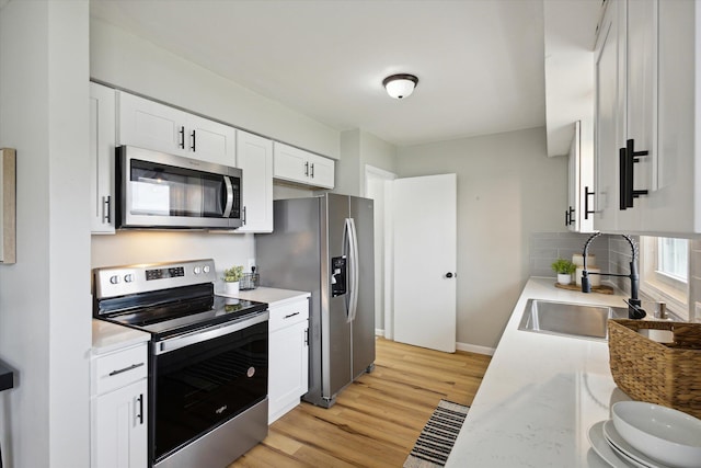 kitchen with white cabinetry, sink, backsplash, light hardwood / wood-style floors, and stainless steel appliances