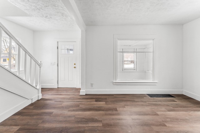 entrance foyer with plenty of natural light, a textured ceiling, and dark hardwood / wood-style flooring