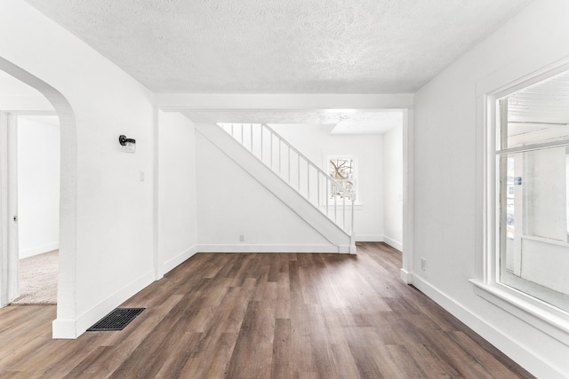 empty room with dark hardwood / wood-style floors and a textured ceiling