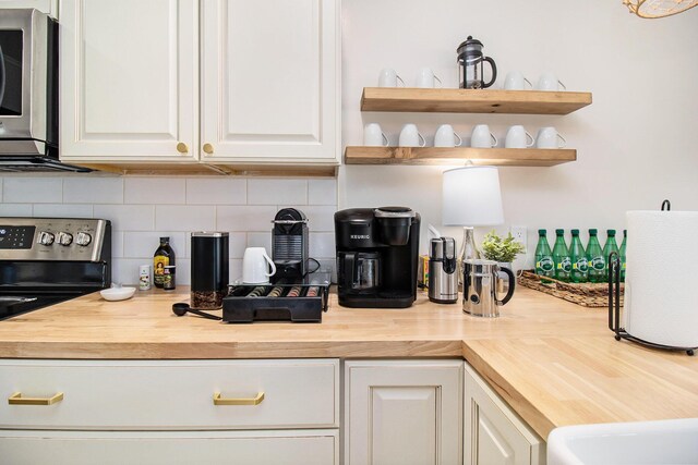 kitchen with white cabinets, backsplash, and butcher block countertops