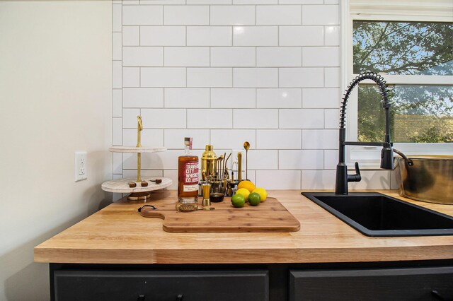 details featuring butcher block countertops, sink, and tasteful backsplash