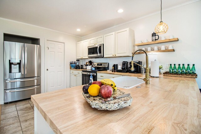 kitchen with pendant lighting, tasteful backsplash, white cabinetry, stainless steel appliances, and crown molding