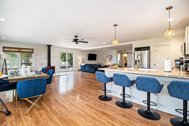 kitchen featuring stainless steel refrigerator with ice dispenser, sink, light hardwood / wood-style flooring, and pendant lighting