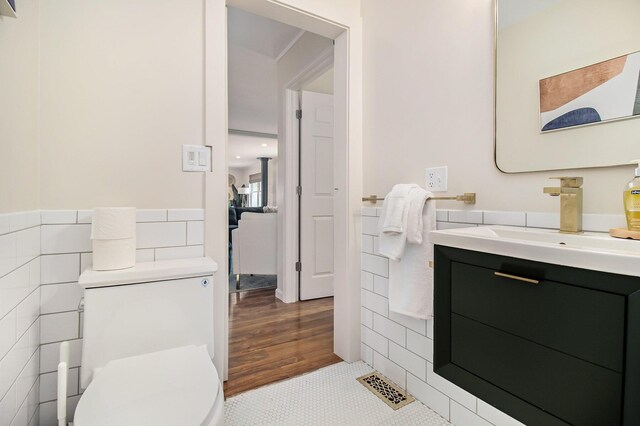 bathroom with hardwood / wood-style flooring, vanity, toilet, and tile walls