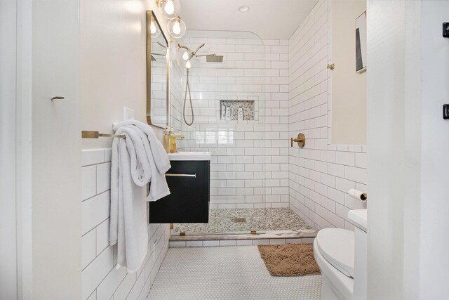 bathroom featuring tile patterned flooring, vanity, a tile shower, and toilet