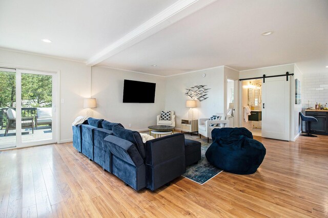 living room with crown molding, a barn door, beam ceiling, and light hardwood / wood-style flooring