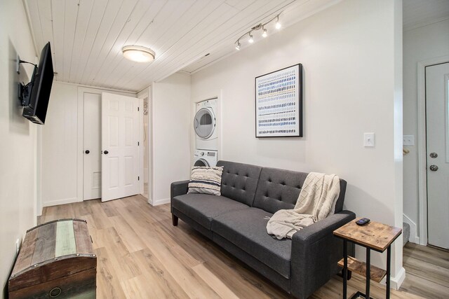 living room with stacked washer and dryer, wood ceiling, and light wood-type flooring