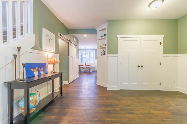 corridor with a barn door and dark hardwood / wood-style floors