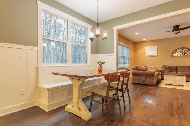 dining area with dark hardwood / wood-style flooring and ceiling fan with notable chandelier