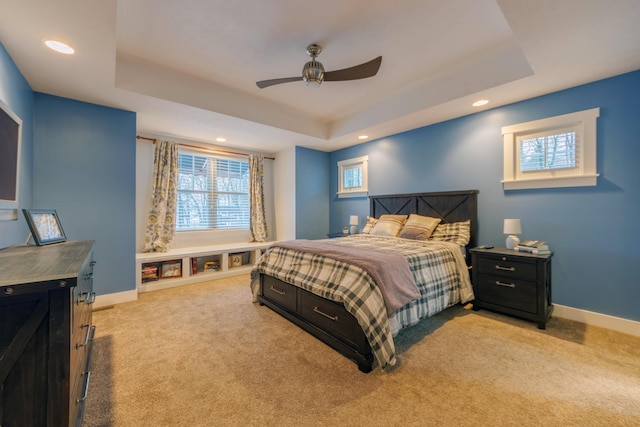 bedroom with a raised ceiling, light carpet, and ceiling fan