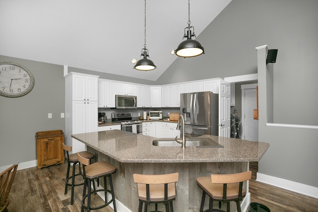 kitchen with stainless steel appliances, dark hardwood / wood-style floors, white cabinets, and decorative light fixtures