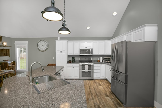 kitchen with stainless steel appliances, dark stone counters, and white cabinets