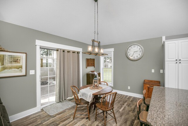 dining area featuring a healthy amount of sunlight, an inviting chandelier, and dark hardwood / wood-style flooring