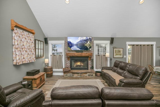 living room with hardwood / wood-style flooring, a healthy amount of sunlight, lofted ceiling, and a fireplace