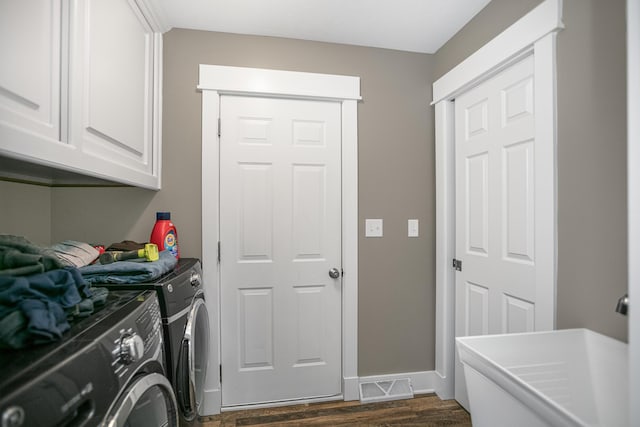 laundry room with dark hardwood / wood-style flooring, cabinets, and washing machine and clothes dryer