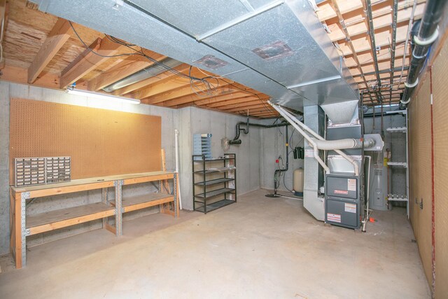 basement with heating unit, a workshop area, and water heater