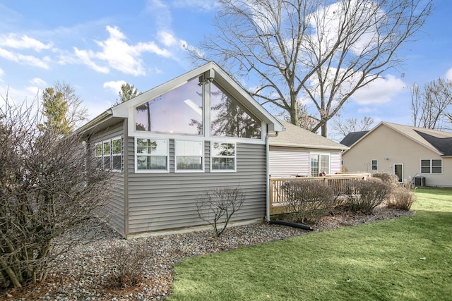 view of side of property featuring a wooden deck, a yard, and central AC