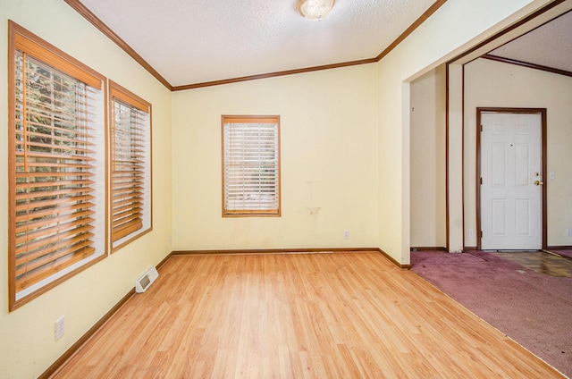 unfurnished room featuring crown molding, vaulted ceiling, a textured ceiling, and light hardwood / wood-style flooring