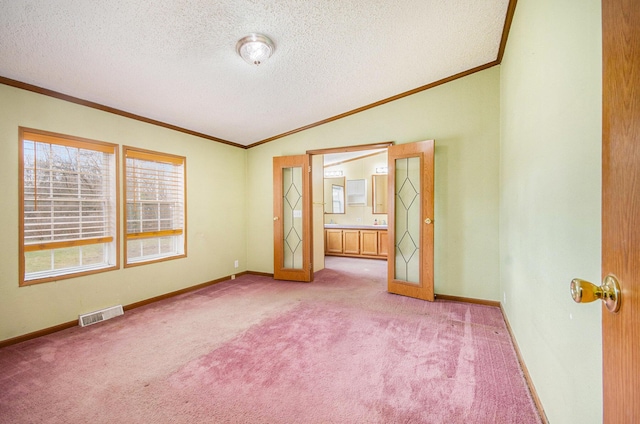 carpeted empty room with crown molding, vaulted ceiling, and a textured ceiling