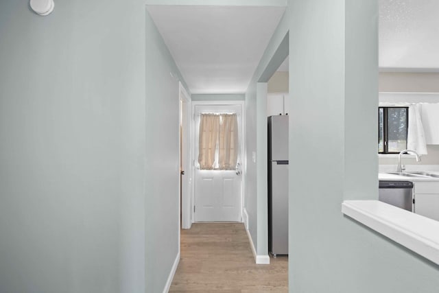 corridor with sink and light wood-type flooring