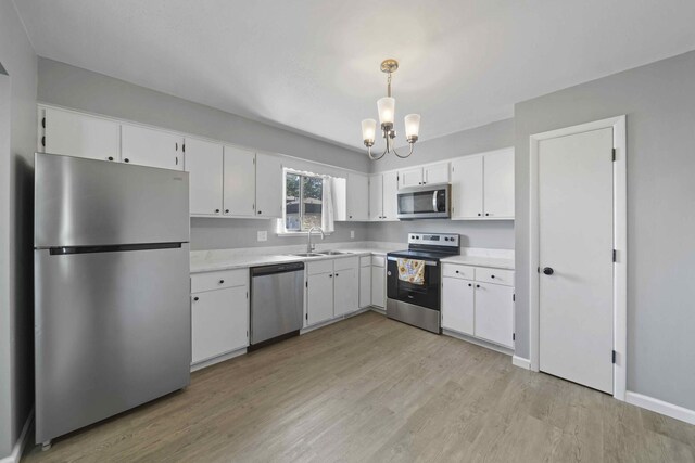 kitchen featuring white cabinetry, sink, decorative light fixtures, and appliances with stainless steel finishes