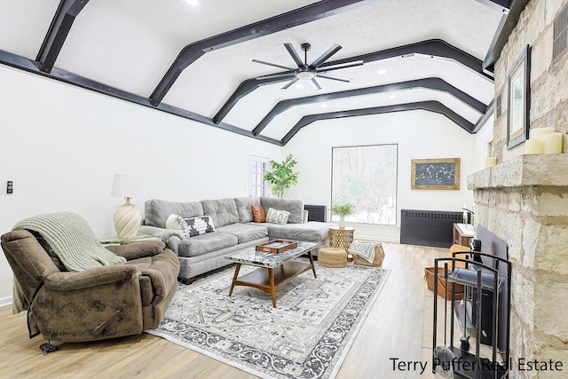 living room with radiator heating unit, a fireplace, lofted ceiling with beams, wood-type flooring, and ceiling fan