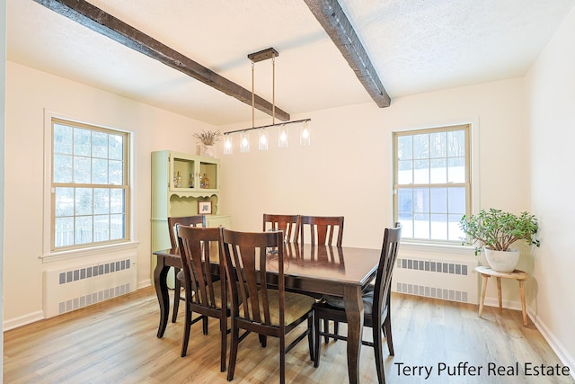 dining area featuring radiator, a textured ceiling, beam ceiling, and light hardwood / wood-style flooring