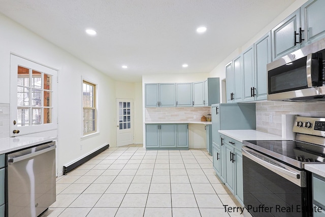 kitchen with tasteful backsplash, stainless steel appliances, baseboard heating, and light tile patterned floors