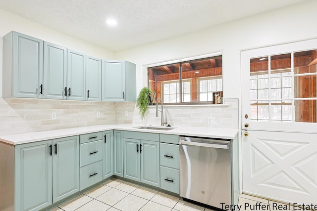 kitchen featuring light tile patterned flooring, tasteful backsplash, sink, stainless steel dishwasher, and a textured ceiling