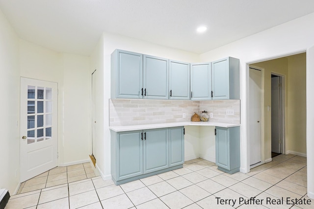 kitchen featuring light tile patterned flooring, blue cabinetry, and decorative backsplash