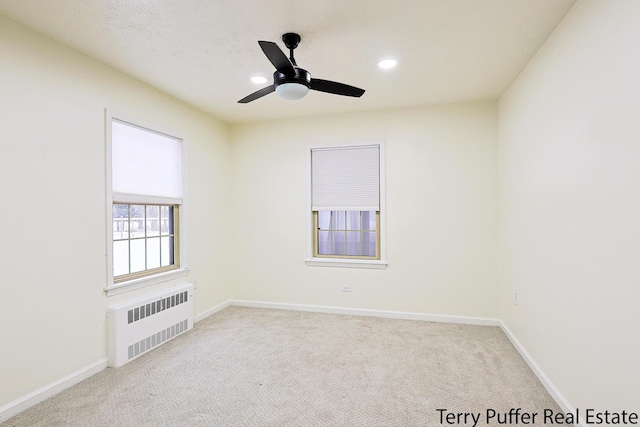 carpeted spare room with ceiling fan and radiator