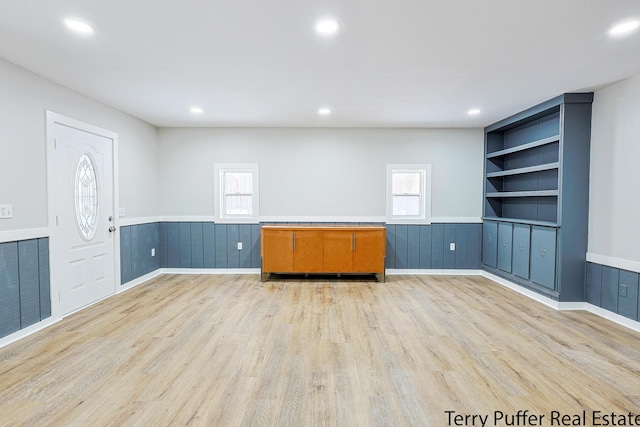 spare room featuring light hardwood / wood-style floors and built in shelves