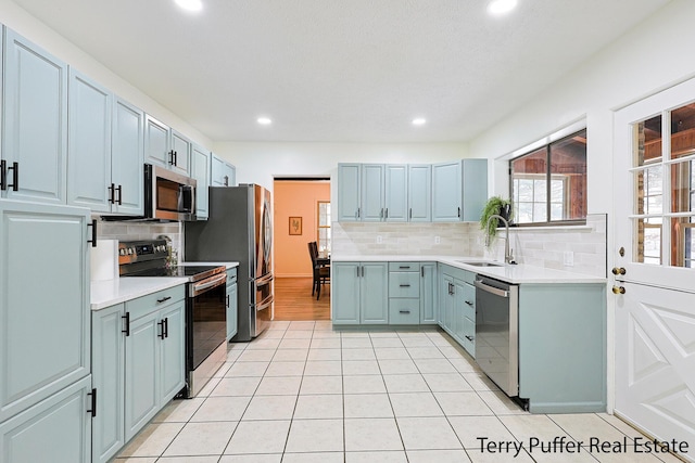 kitchen featuring sink, decorative backsplash, stainless steel appliances, and light tile patterned floors