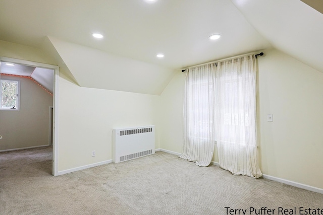 bonus room featuring lofted ceiling, radiator, and light carpet