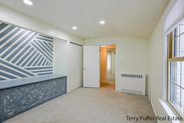 unfurnished bedroom with light colored carpet, radiator, and multiple windows