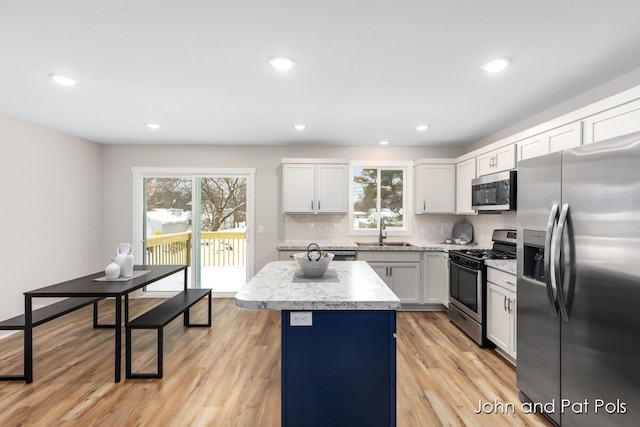 kitchen featuring sink, stainless steel appliances, a center island, a healthy amount of sunlight, and white cabinets