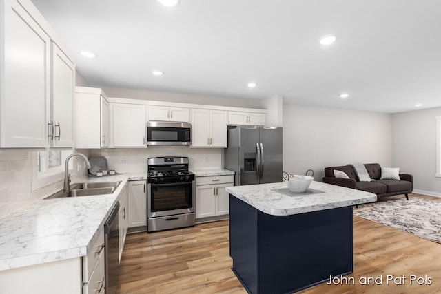 kitchen with sink, white cabinets, a center island, stainless steel appliances, and light wood-type flooring