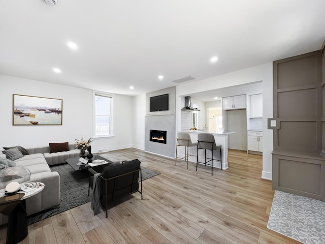 living room with a large fireplace and light hardwood / wood-style flooring