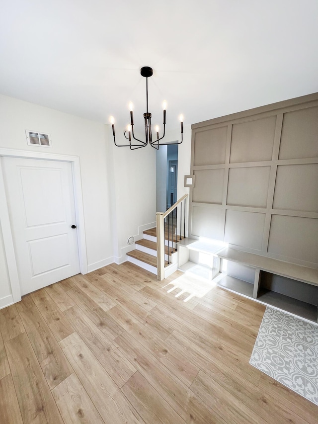 unfurnished dining area with a chandelier and light wood-type flooring