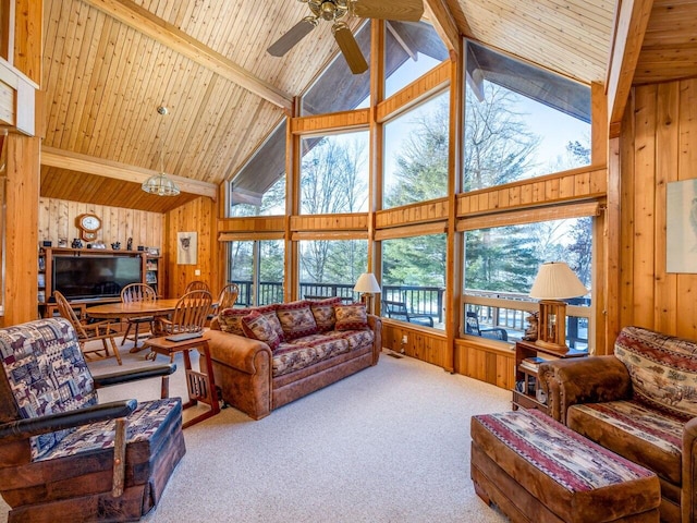 carpeted living room featuring beamed ceiling, ceiling fan, wood ceiling, and wooden walls