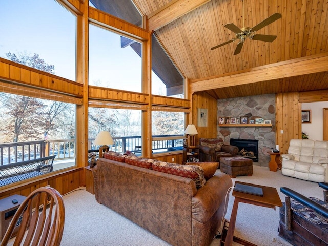 carpeted living room with beam ceiling, plenty of natural light, wooden ceiling, and a stone fireplace