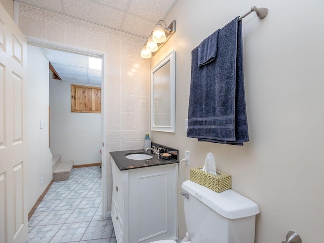 bathroom with vanity, toilet, and a drop ceiling