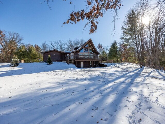 snow covered back of property with a deck